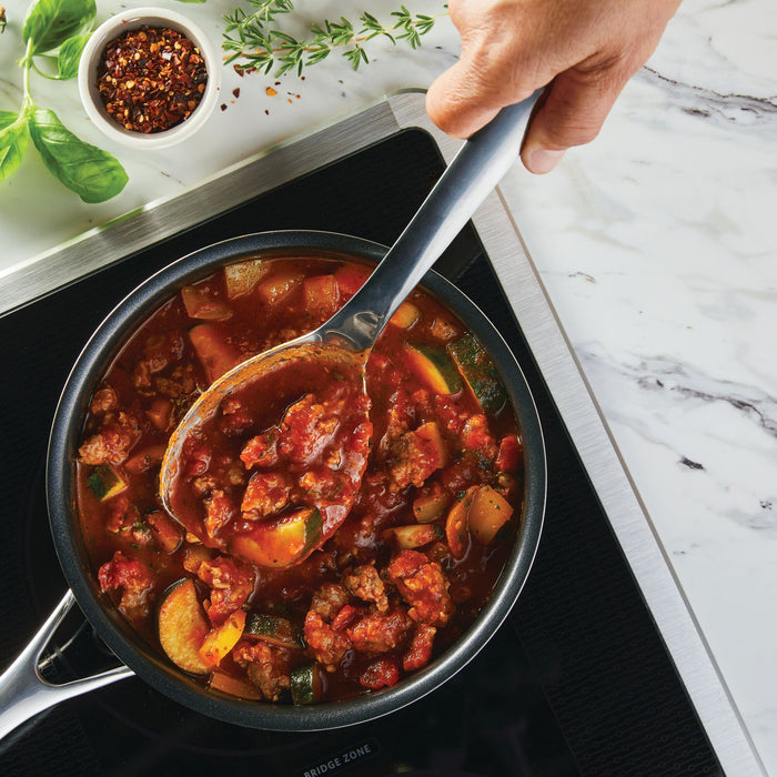 Using the 3-Piece Kitchen Utensils Set, a person stirs a hearty vegetable and meat stew in a pot on the stove, enjoying both comfort and precision with stainless steel tools designed with ergonomic handles.