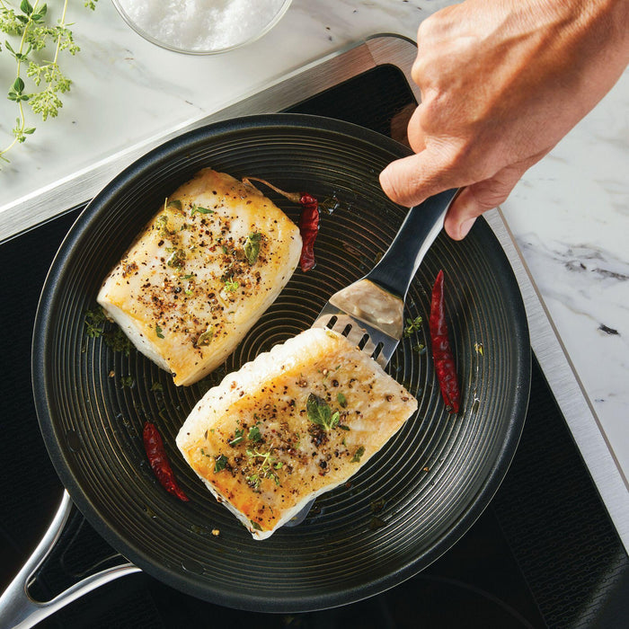 With the 3-Piece Kitchen Utensils Set, a person expertly grills fish fillets with herbs and spices in a pan, highlighting the finesse of stainless steel kitchen tools featuring ergonomic handles.