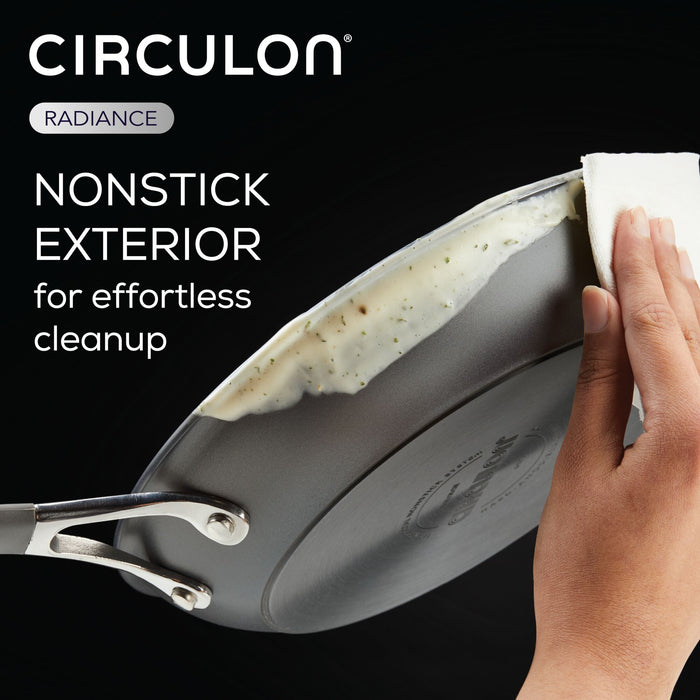 Hands using a paper towel to clean food residue from a 3-Quart Nonstick Straining Saucepan.