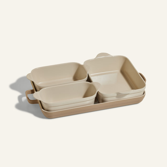 The Bakeware Set includes four beige ceramic bakers with handles, nested together—an ideal addition to any kitchen collection.