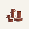 The Dinnerware Set includes stacked brown ceramic mugs, bowls, small plates, and large plates, all displayed against a plain light background.