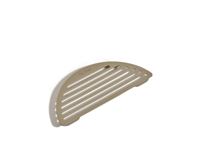 The Fry Deck is a beige, semi-circular slotted rack with "Our Place" engraved on its flat surface, ideal as a frying accessory. Photographed on a white background.
