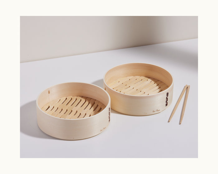 Two handmade Mini Spruce Steamers sit side by side on a white surface, accompanied by bamboo chopsticks.