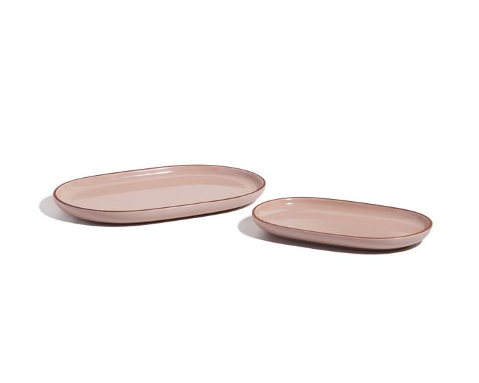 Two oval, light pink Serving Platters of different sizes are arranged side by side on a white background, forming a stylish tableware set.
