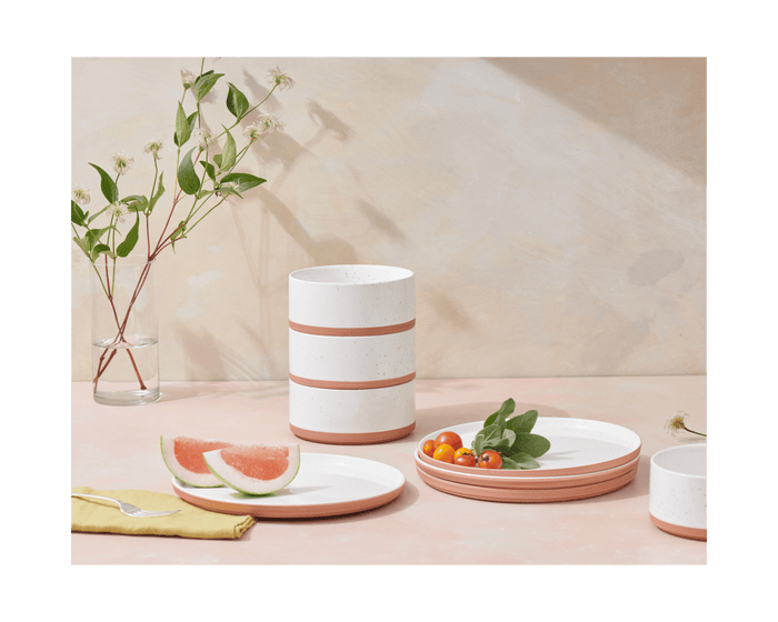 Side Bowls in white and terracotta are shown on a pink surface, paired with hand-painted bowls, fruit plates, and a vase with green branches.