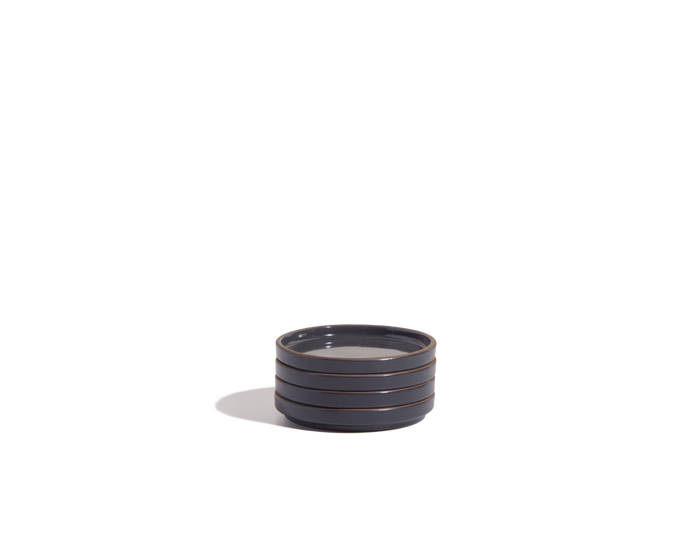 The Tiny Plates are small, round ceramic snack plates in dark gray with three horizontal ridges, displayed against a plain white background.